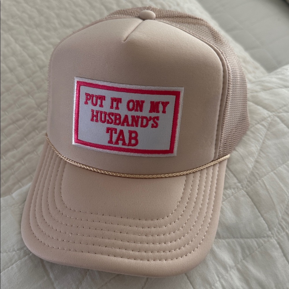 Brand new Beige Trucker Hat “Put it on my Husband’s Tab”.  Beige w/Pink writing